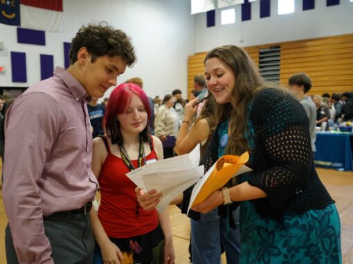 Ashe County GEAR UP Coordinator Hope Gambill, right in foreground, reviews resumes with students during a career fair event at Ashe County High School in April 2026. The event provided students with a free resume workshop and information on local career paths.